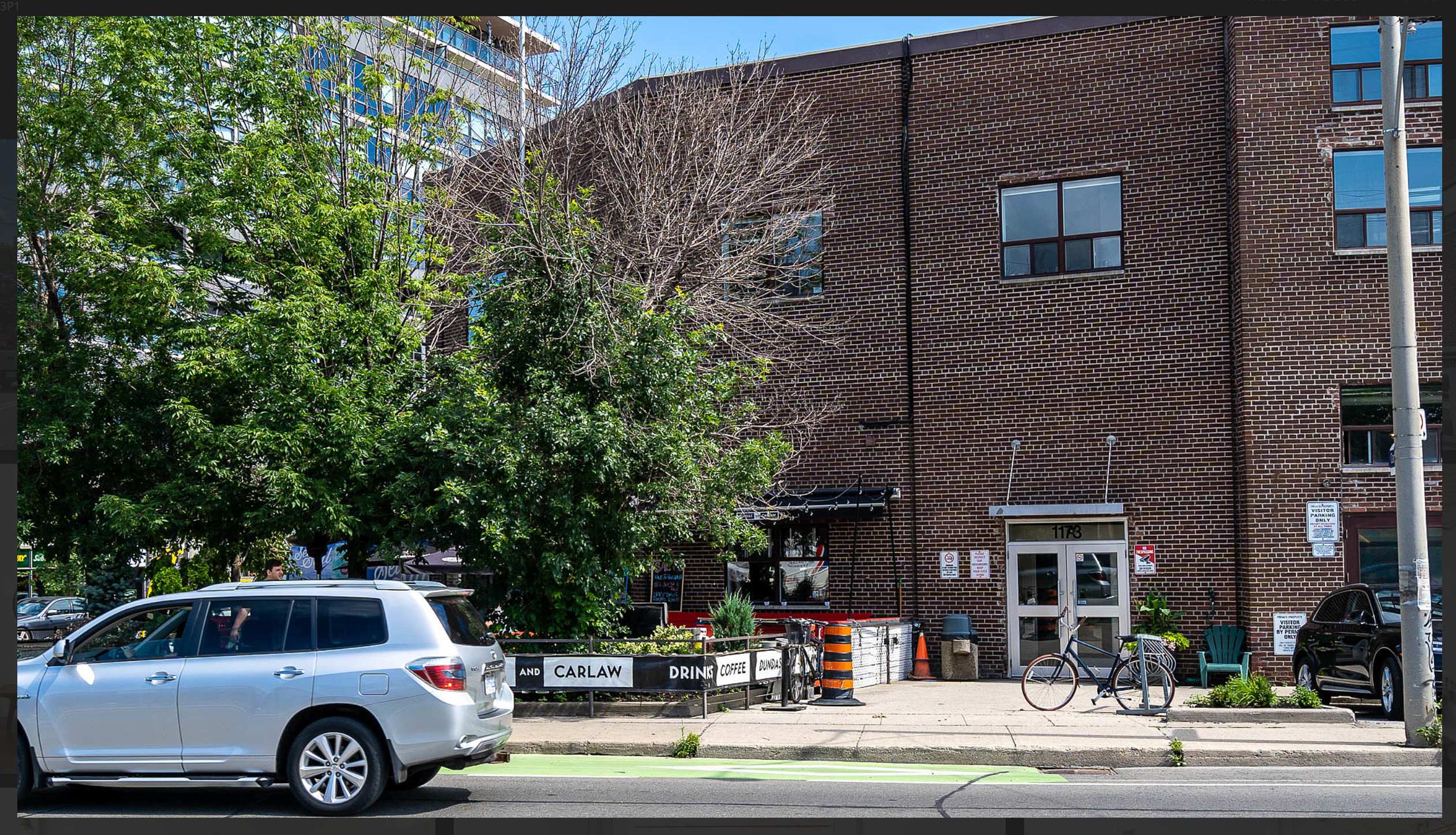 Dundas and Carlaw intersection — brick building, green bike lane, coffee shop with pedestrian crossing unprotected
